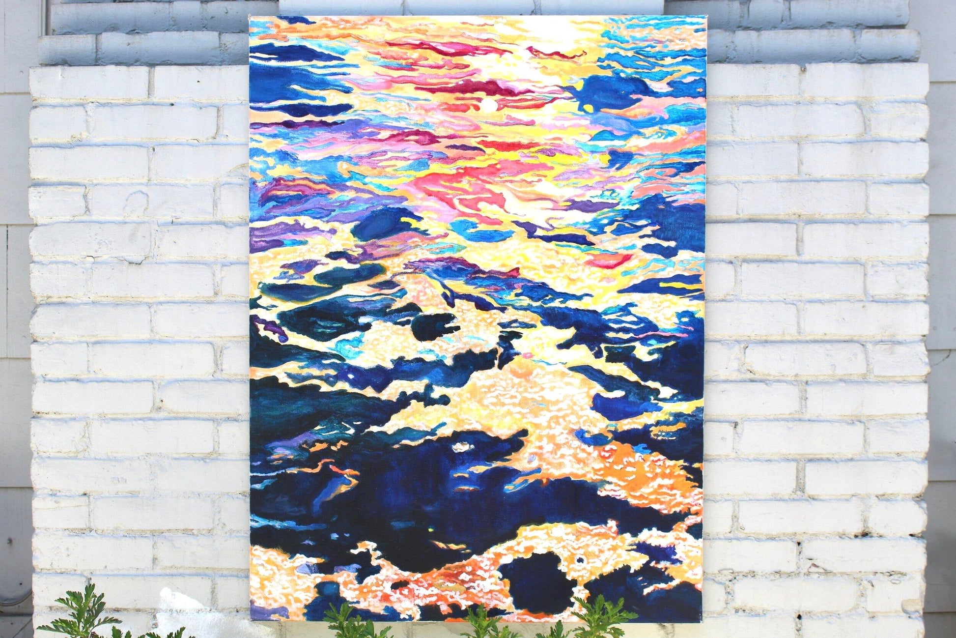 painting of a closeup of the ocean during sunset hanging on grey brick wall