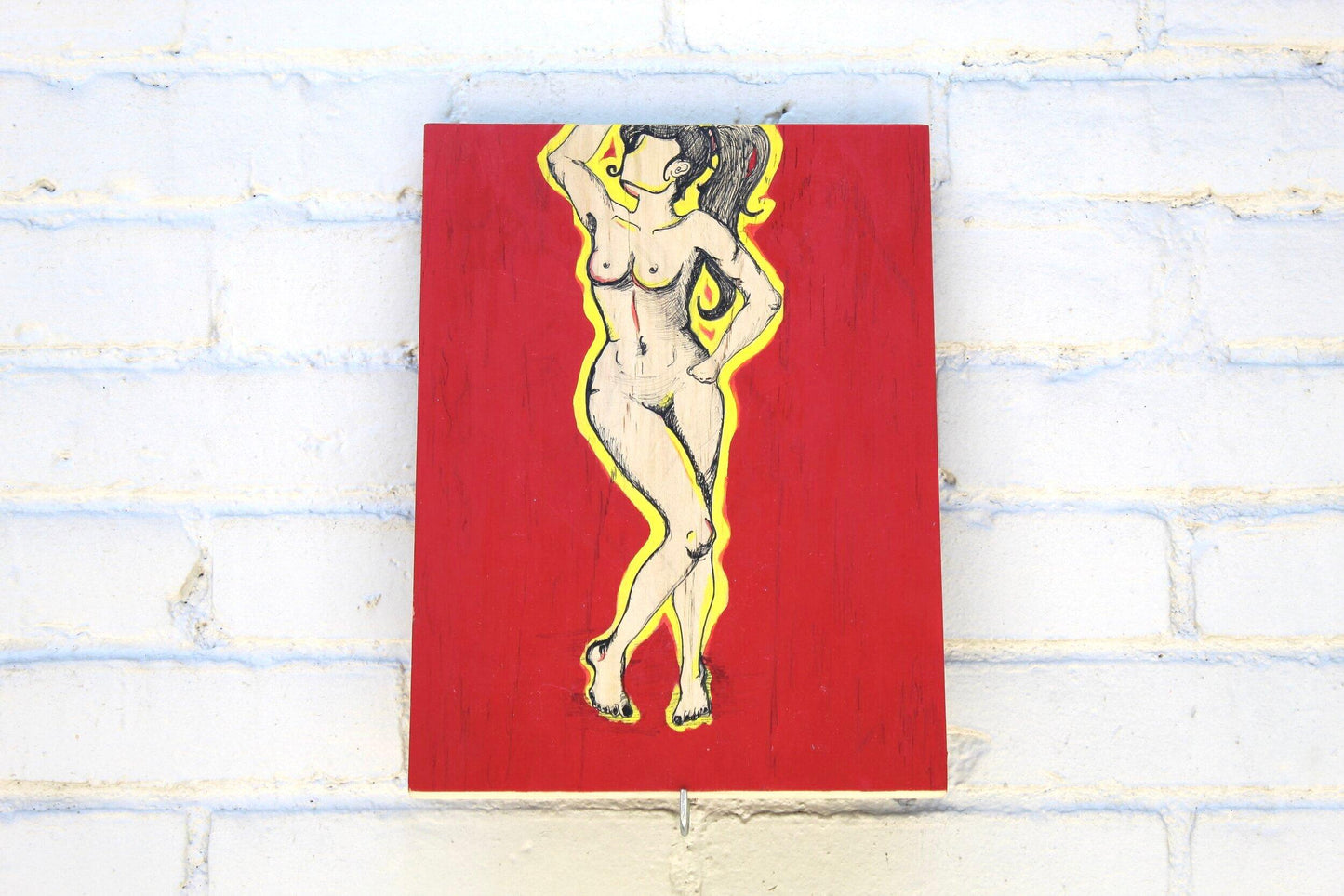 lllustration of nude pen drawn woman with yellow outline and red background on grey brick wall 