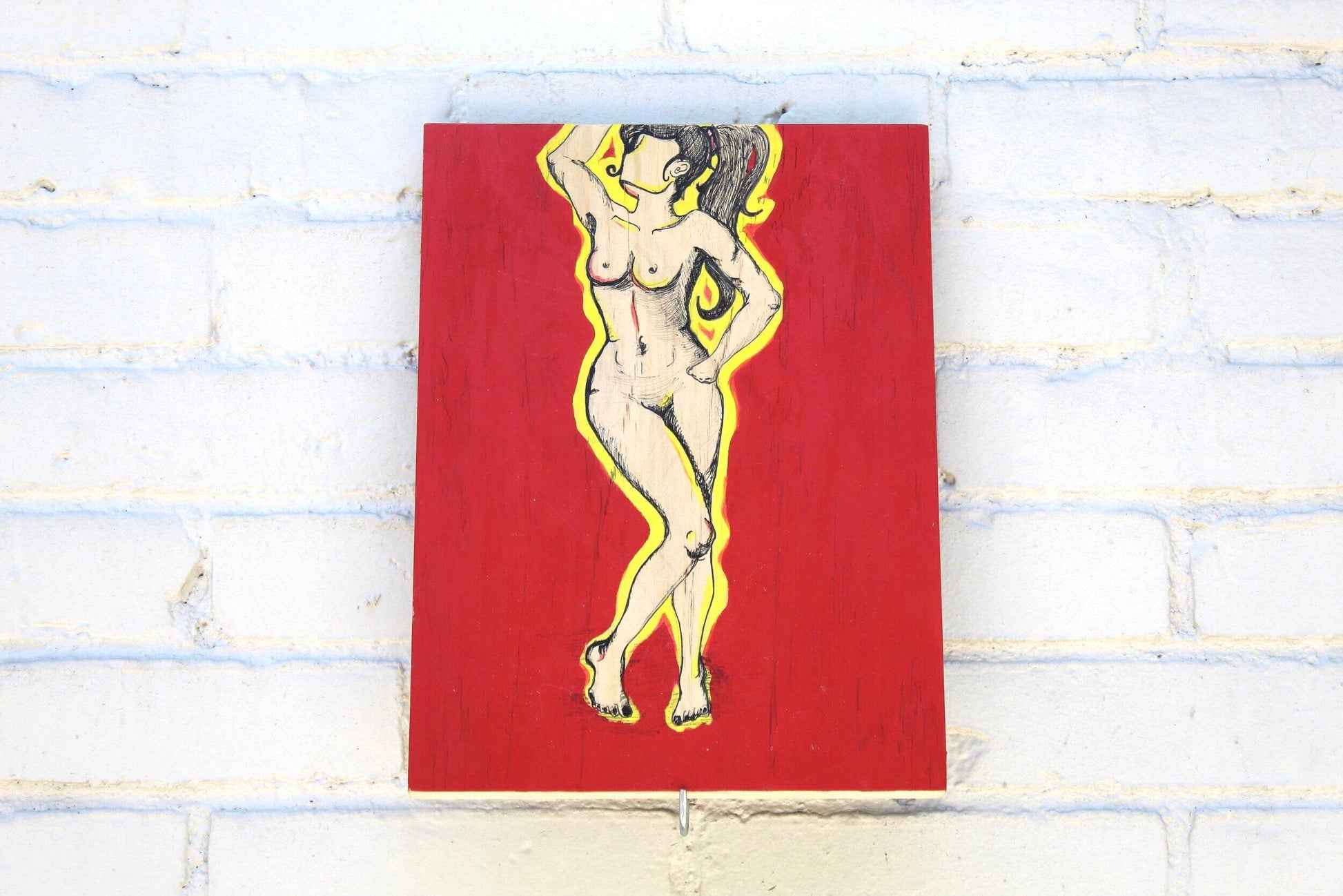 lllustration of nude pen drawn woman with yellow outline and red background on grey brick wall 