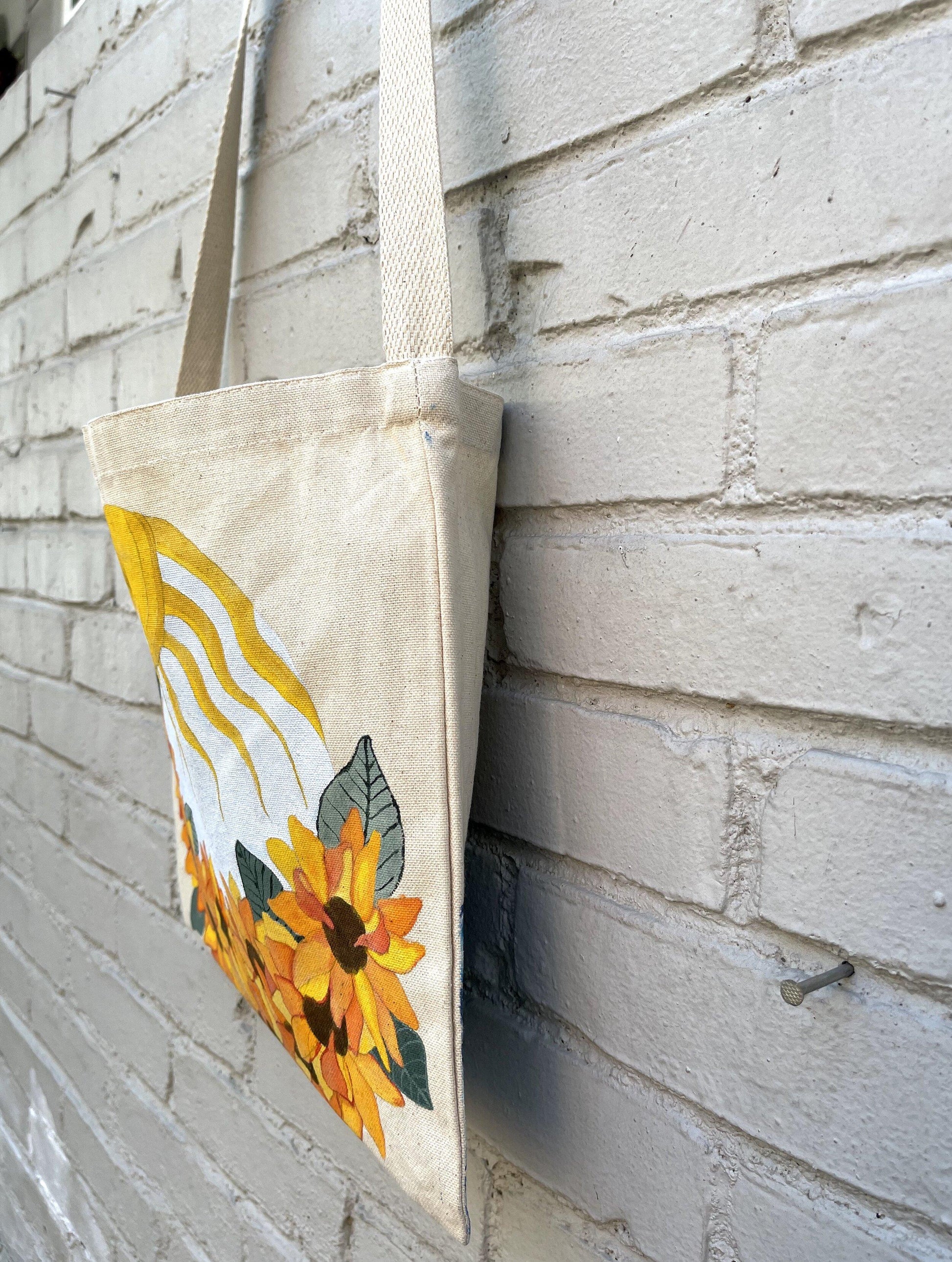 side view of canvas tote bag with painting of sunflowers and sun